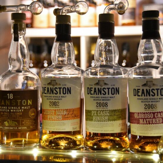 Flaschen von Deanston Whisky glänzen auf einem Messestand.