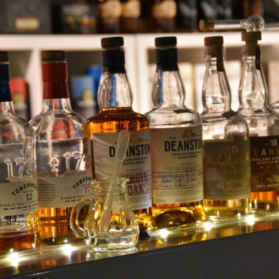 Flaschen von Tobermory und Deanston Whisky werden mit stimmungsvoller Beleuchtung von unten auf dem Bottle Market Bremen präsentiert.