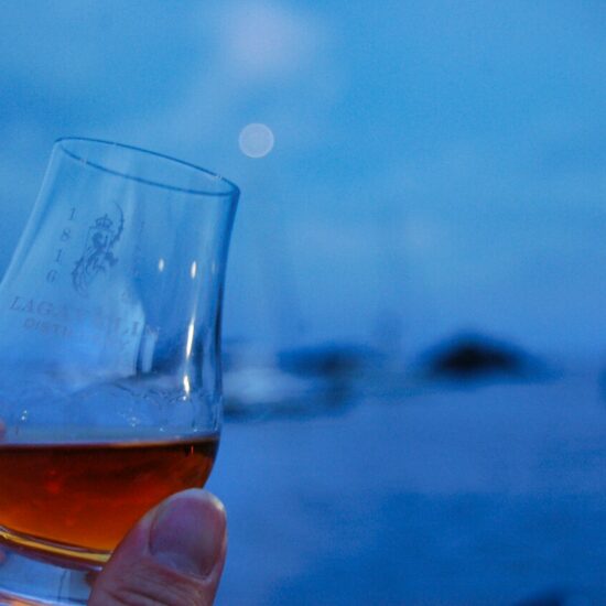 Whiskglas von Lagavulin in Blauer Stunde am Meer.